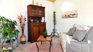 Una sala de estar con techo de madera, un mueble con puertas de cristal, un sofá, una mesa de centro y un cuadro en la pared.