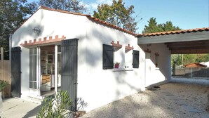 Una casa blanca con techo de tejas, puerta de garaje y entrada de grava.