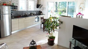 Una cocina moderna con protector contra salpicaduras de pared de piedra, techo de madera y ventanas amplias.