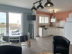 Eine moderne Küche mit Essbereich, einem Balkon mit Aussicht und einem an der Wand befestigten Flachbildfernseher.