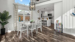 A modern kitchen with white cabinets, a microwave, and a dining area with a white table and chairs.