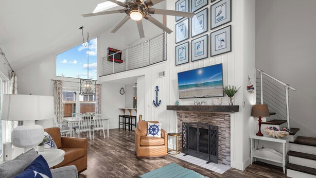 A spacious living area with a fireplace, a dining area, and a staircase.
