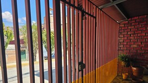 A room with a red and yellow striped gate, a brick wall, and a patterned floor. - 2-bedroom house in Huaraz. 10 minute walk from Plaza de Armas (Huaraz)