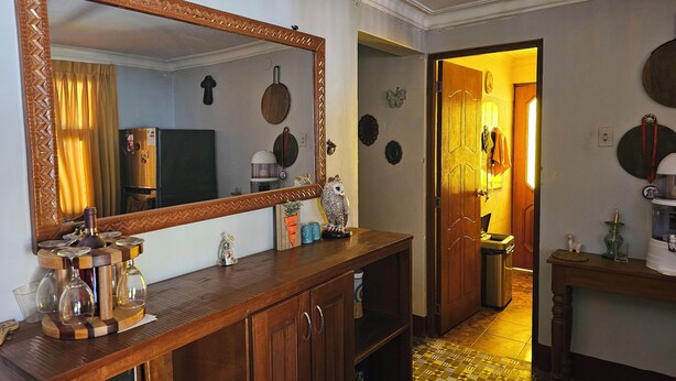 A hallway with a wooden cabinet, a large mirror, and a door leading to another room. - 2-bedroom house in Huaraz. 10 minute walk from Plaza de Armas (Huaraz)