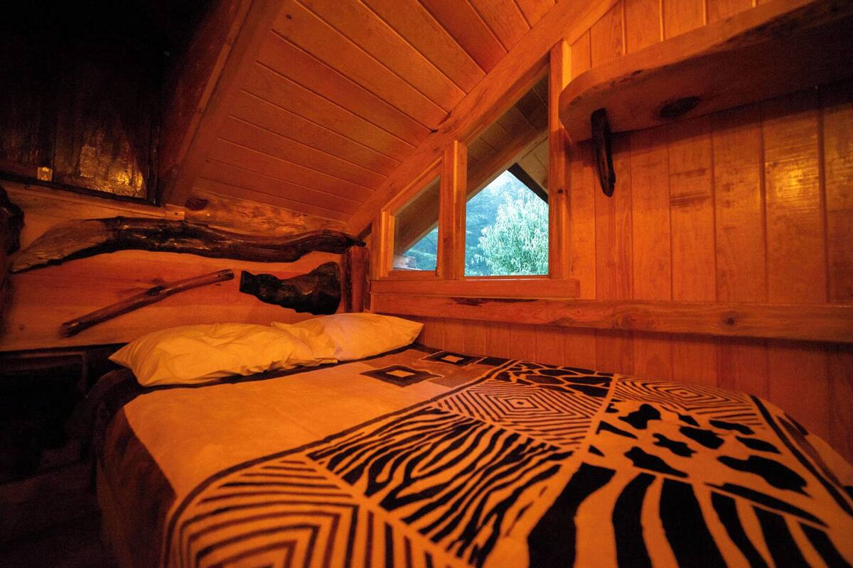 Ein gemütliches Blockhäuschenzimmer mit einem Bett, einem Fenster und Holzwänden.
