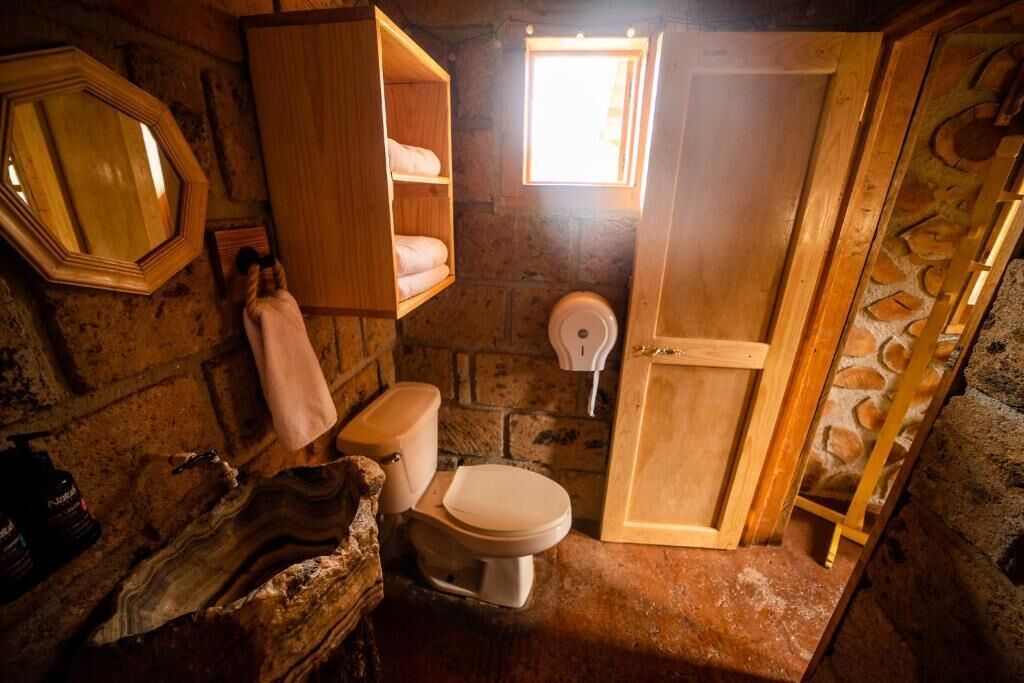Ein rustikales Badezimmer mit einem Holzbadezimmer-Möbel, einer Toilette und einem kleinen Fenster.