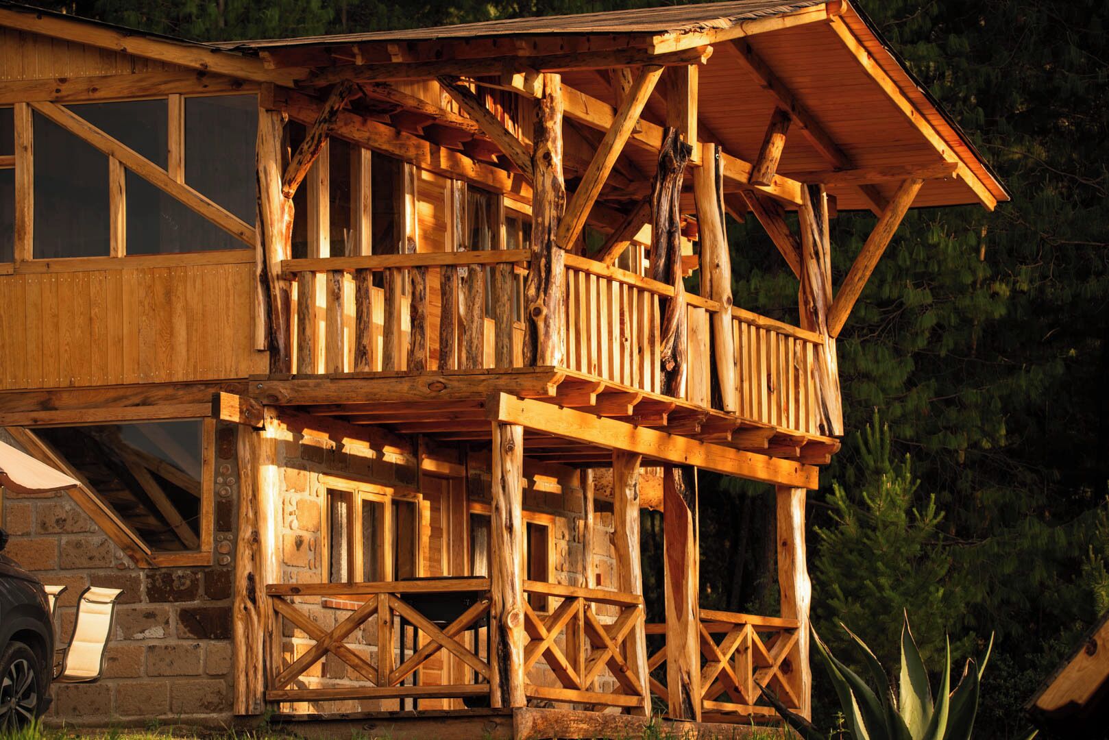 A wooden cabin with a balcony and a stone foundation.