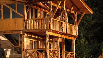 A wooden cabin with a balcony and a stone foundation.