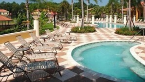 Un área de piscina con sillas de descanso y palmeras.