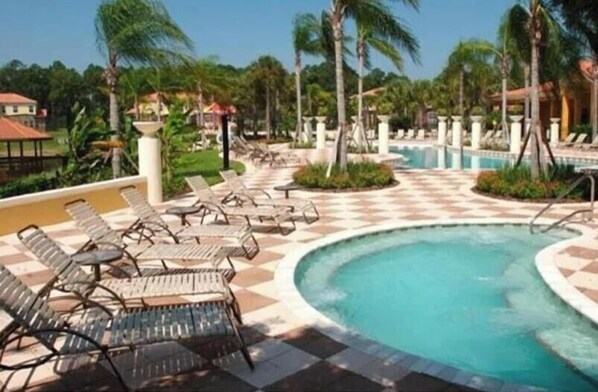 A pool area with lounge chairs and palm trees. - 3004 RG - Encantada Serene Retreat Private Hot Tub (Kissimmee)