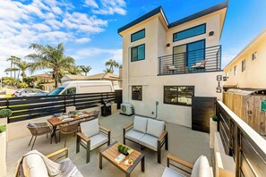 Une maison moderne à deux étages, dotée d’un balcon, de mobilier d’extérieur et d’un fourgon garé dans l’allée.