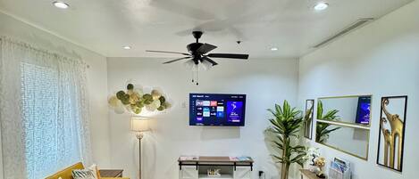 Una sala de estar con sofá, mesa de centro, televisor y elementos decorativos.