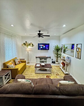 A living room with a sofa, coffee table, TV, and decorative items. - The Prestige 3BR/2BA Condo Near Mall, Airport & Hospitals (McAllen)
