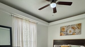 A bedroom with a bed, a ceiling fan, a dresser, a painting, and a patterned rug. - The Prestige 3BR/2BA Place Near Airport and Mall (McAllen)