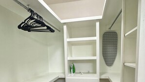 A walk-in closet with white shelving, a black cabinet, and an ironing board. - The Prestige 3BR/2BA Place Near Airport and Mall (McAllen)