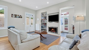 A living room with a fireplace, a television, and a bookshelf. - Elenora history in the heart of town (Queenscliff)