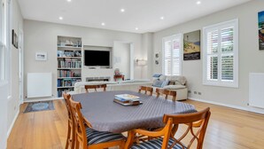 Un salon moderne comprenant un coin repas, un téléviseur à écran plat et une bibliothèque.