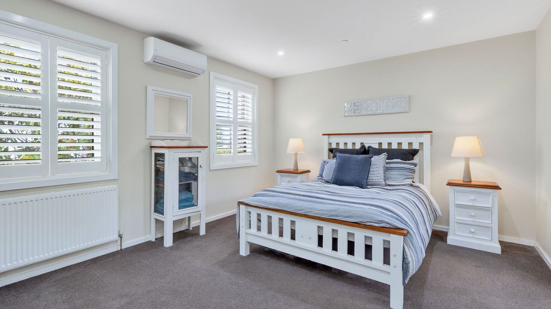 A bedroom with a bed, bedside tables, a mirror, and a radiator.
