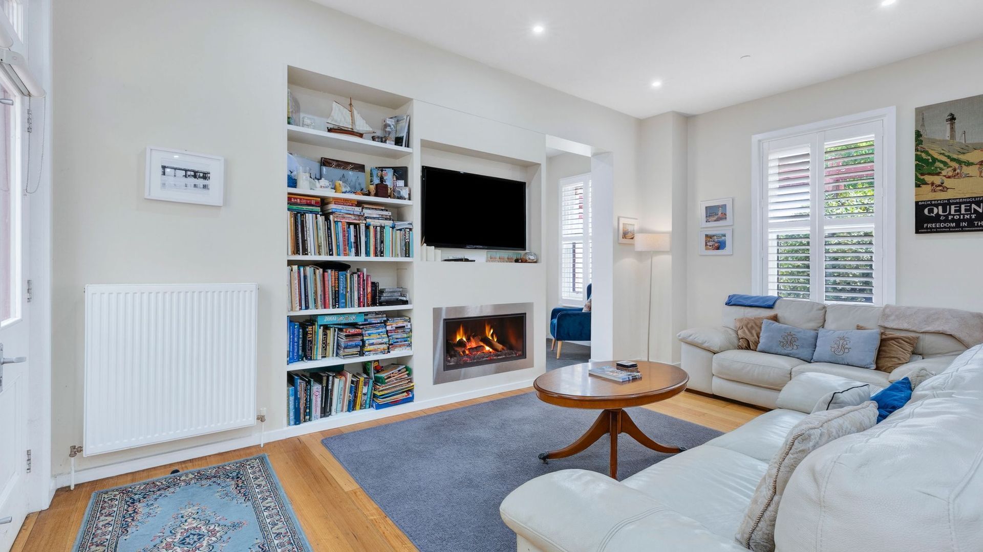 A living room with a fireplace, bookshelves, a sofa, and a television.