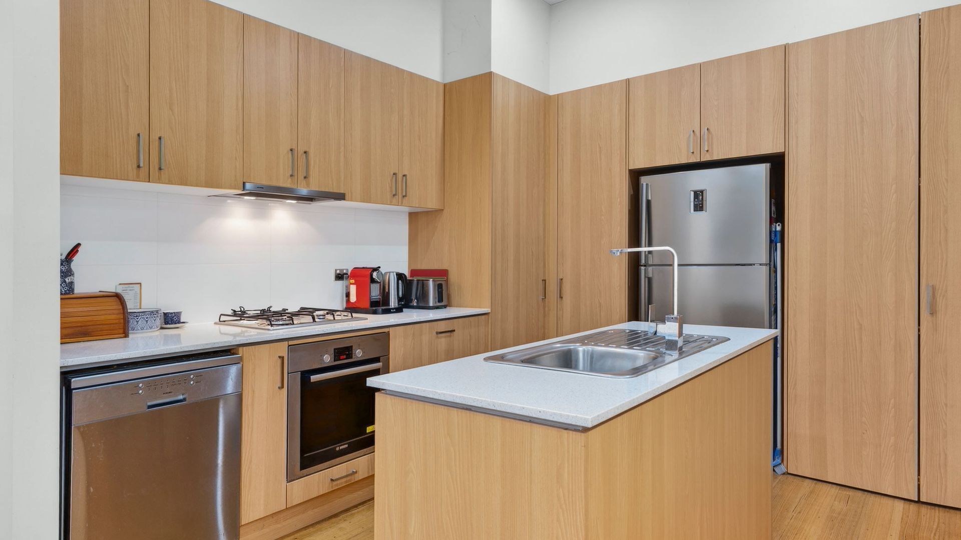 A modern kitchen with wooden cabinets, stainless steel appliances, and a built-in dishwasher.
