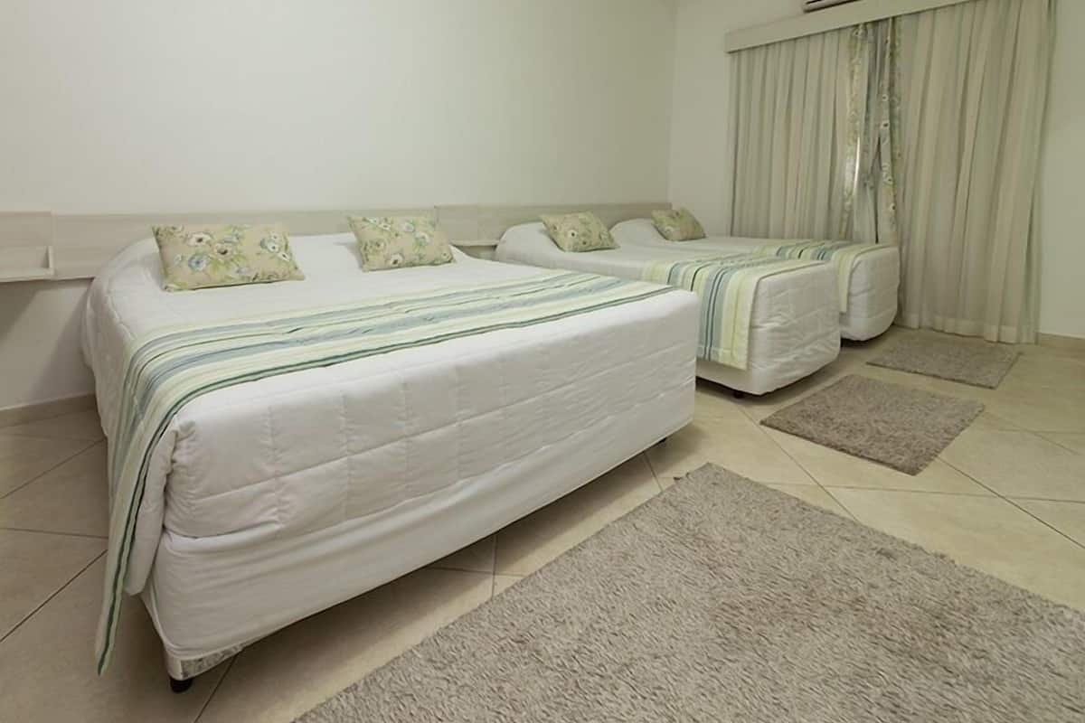 A hotel room with two beds, a window with curtains, a ceiling fan, and a tiled floor.