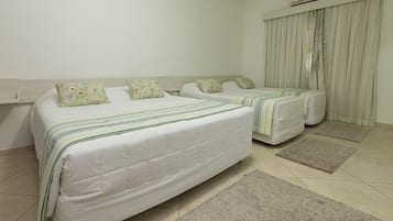 Una habitación de hotel con dos camas, una ventana con cortinas, un ventilador de techo y piso de baldosas.