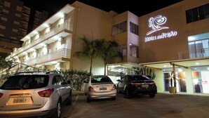 Un hotel con facciata moderna, diversi balconi e un'area di parcheggio con diverse auto.