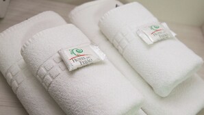Tres tovellons blancs ben plegats amb el logotip d'Hotel do Feijo, damunt una superfície de fusta.