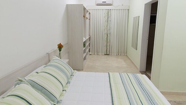 Una camera da letto con un letto, un armadio, uno specchio e una porta che conduce al bagno.