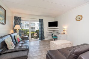 A living room with a leather sofa, a television, and a desk with a lamp. - Ocean Block Retreat – Sleeps 6! (Ocean City)
