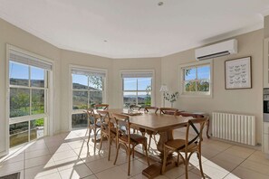 A dining room with a large wooden table and chairs, large windows with views of hills, an air conditioning unit, and a radiator. - Luxe Countryside Home - Amazing Views, Sleeps 6 (Byng)