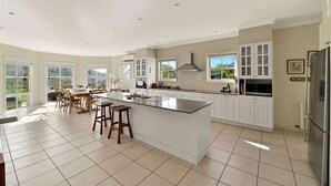 A spacious kitchen with a large island, white cabinetry, and a view of the outdoors.