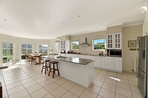 A spacious kitchen with a large island, white cabinetry, and a view of the outdoors. - Luxe Countryside Home - Amazing Views, Sleeps 6 (Byng)