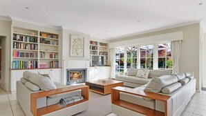A modern living room with a fireplace, two sofas, a coffee table, and a bookshelf filled with books.