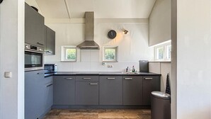 A compact kitchen with built-in appliances, a window, and a clock. - Pet friendly home in Witmarsum with WiFi (Witmarsum)