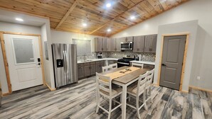 A modern kitchen with wooden cabinets, stainless steel appliances, and a dining area with a wooden table and chairs.