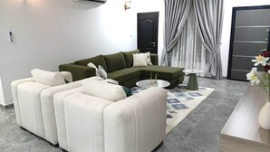 Ein modernes Wohnzimmer mit einer Eckcouch, einem runden Couchtisch und einem Beistelltisch.