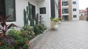 Un edifici amb un pati enrajolat, plantes en testos i una paret exterior blanca.