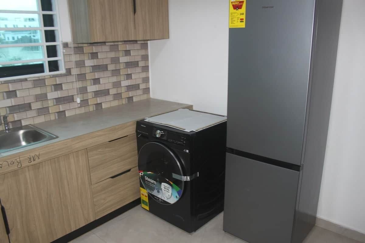 Una cocina compacta con lavadora, refrigerador y ventana con vista.