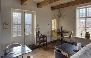 Une pièce chaleureuse avec un plafond en bois, un vitrail, une table ronde entourée de chaises et un canapé.