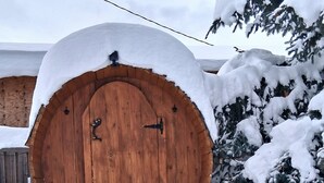 Une porte de grange en bois recouverte de neige, avec un arbre également couvert de neige sur la droite.