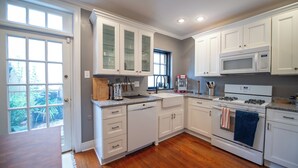 A kitchen with white cabinets, a dishwasher, a stove, and a microwave. - 2-Bdr 2.5Ba House in Enchanting Philadelphia Neighborhood, AC & Private Backyard (Philadelphia)