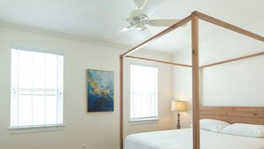 A four-poster bed with a wooden frame and white bedding in a room with wooden flooring, a ceiling fan, and two windows with blinds. - 2-Bdr 2.5Ba House in Enchanting Philadelphia Neighborhood, AC & Private Backyard (Philadelphia)