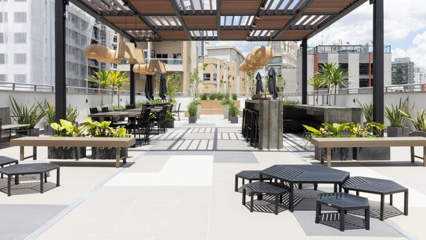Eine Dachterrasse mit Sitzgelegenheiten im Freien, Pflanzgefäßen und einer Pergola.