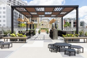 A rooftop terrace with outdoor seating, planters, and a pergola structure. - Moderno com AC piscina e academia (São Paulo)