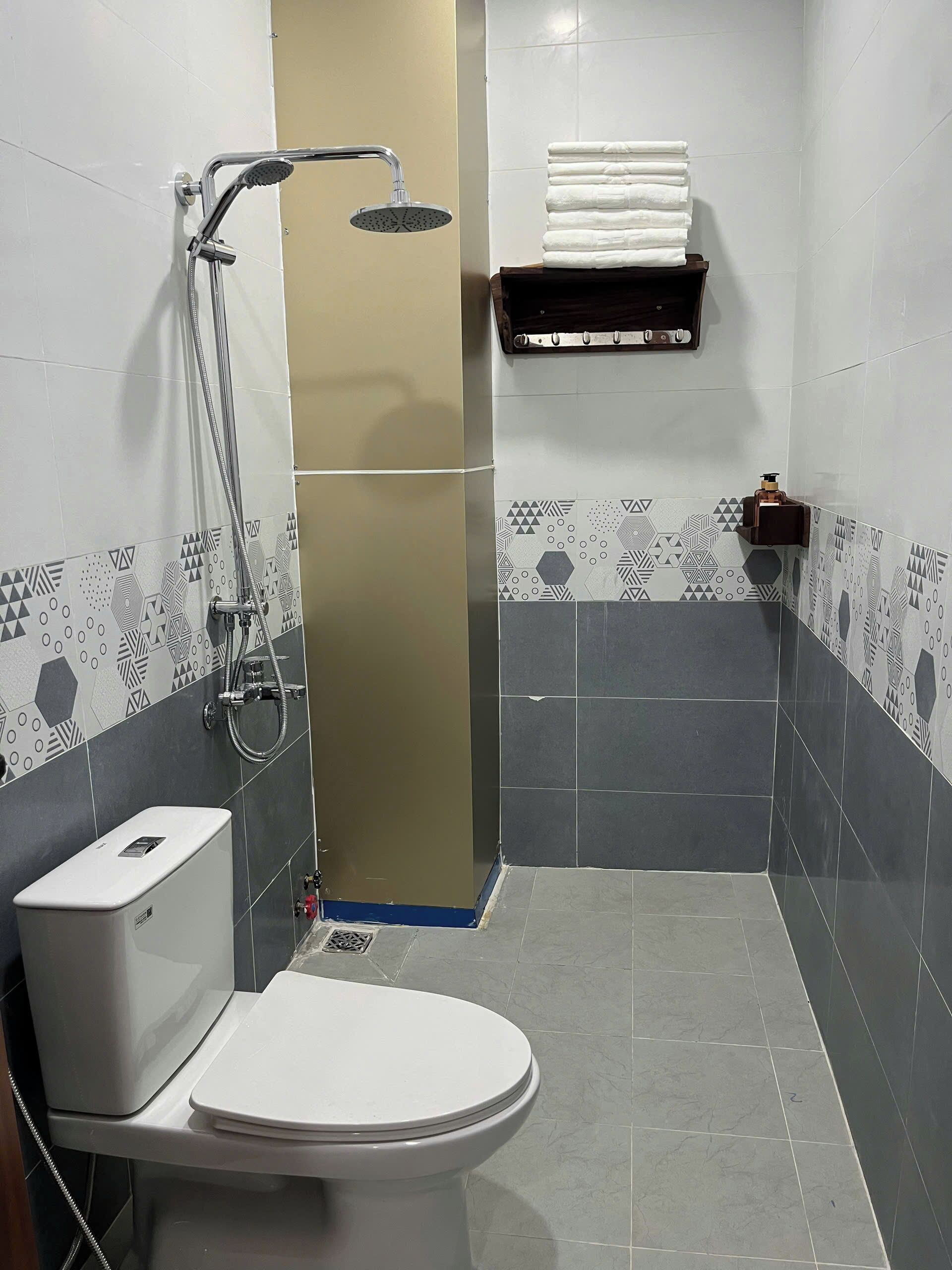A bathroom with a toilet, shower, and a towel rack.