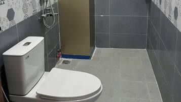 A bathroom with a toilet, shower, and a towel rack.
