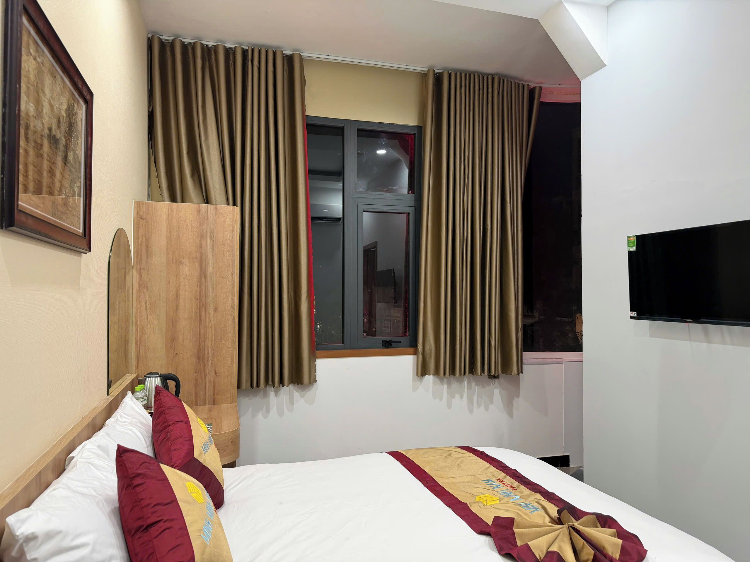 Una camera d'albergo con un letto, tende, una televisione e una finestra.