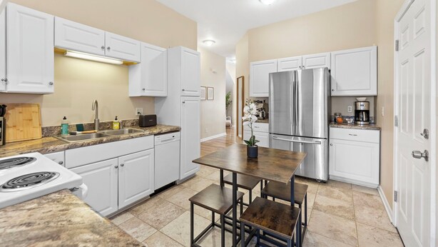 A modern kitchen with white cabinets, a stainless steel refrigerator, and a granite countertop. - Charming KC 2BR 1 BATH Downtown Access In-Unit Laundry (Kansas City)