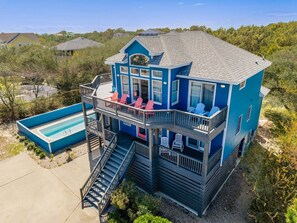 A two-story house with a balcony, a pool, and a staircase leading to the upper level. - Luxury Cottage Pool, Hot Tub, Walk to Beach (Corolla)